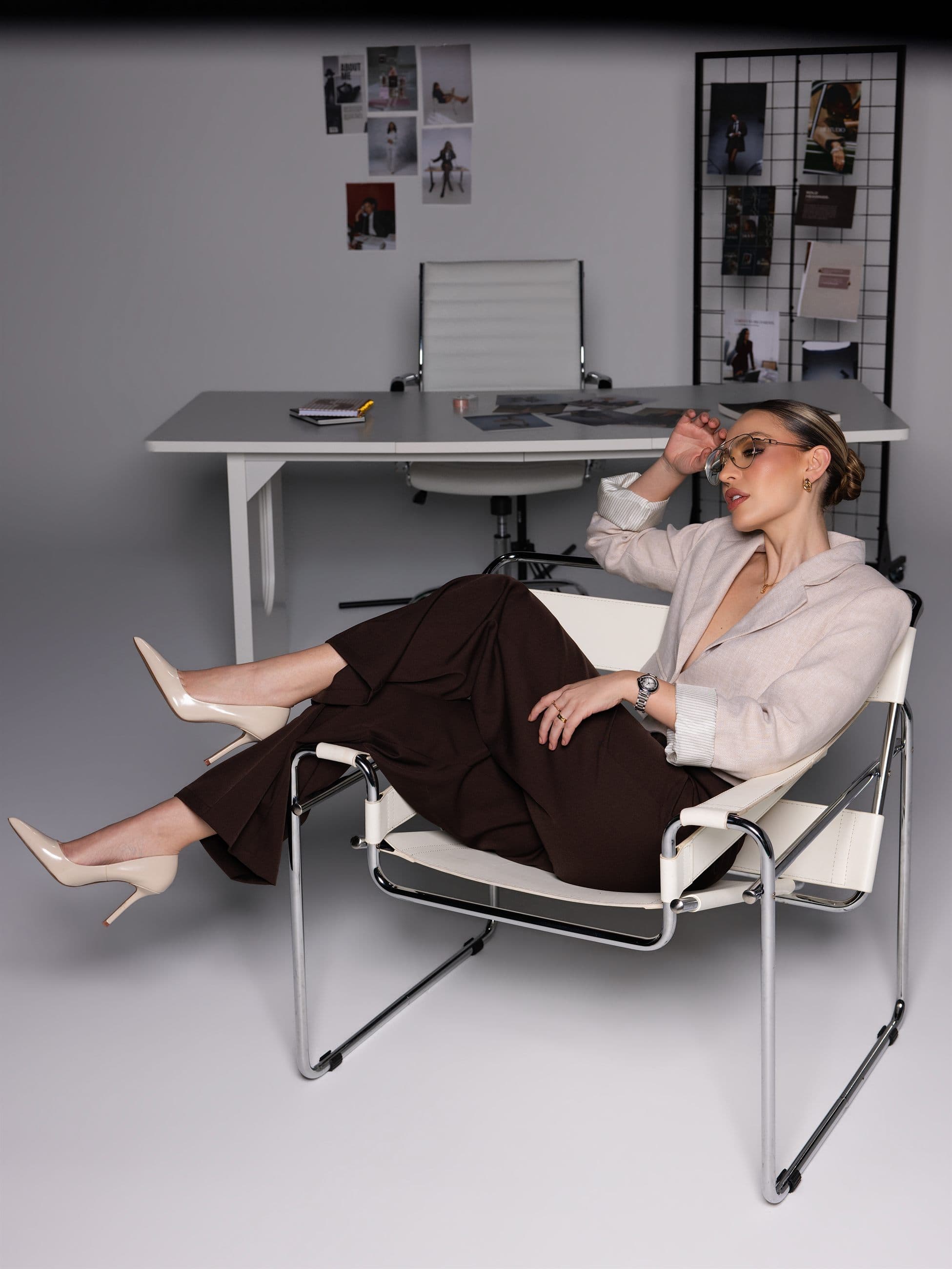 Laura Rentería reclining in the studio beside a desk and moodboard.