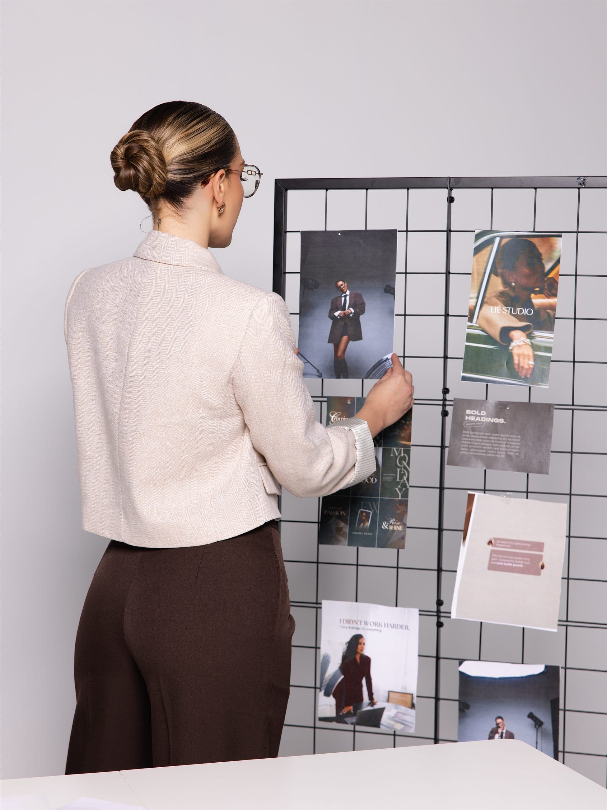 Laura Rentería arranging references on a studio moodboard, seen from behind.